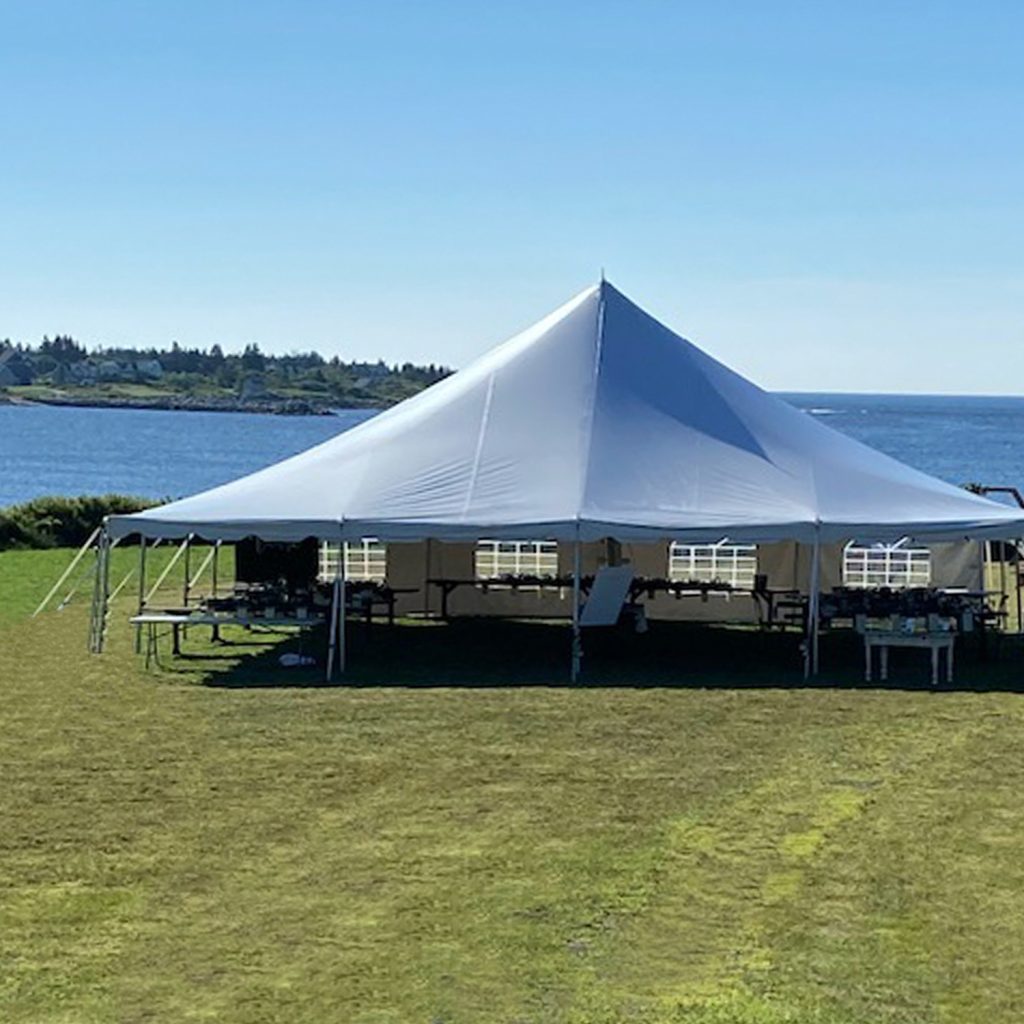 Photo of an event tent set up on the front lawn, near the water, for a wedding reception.