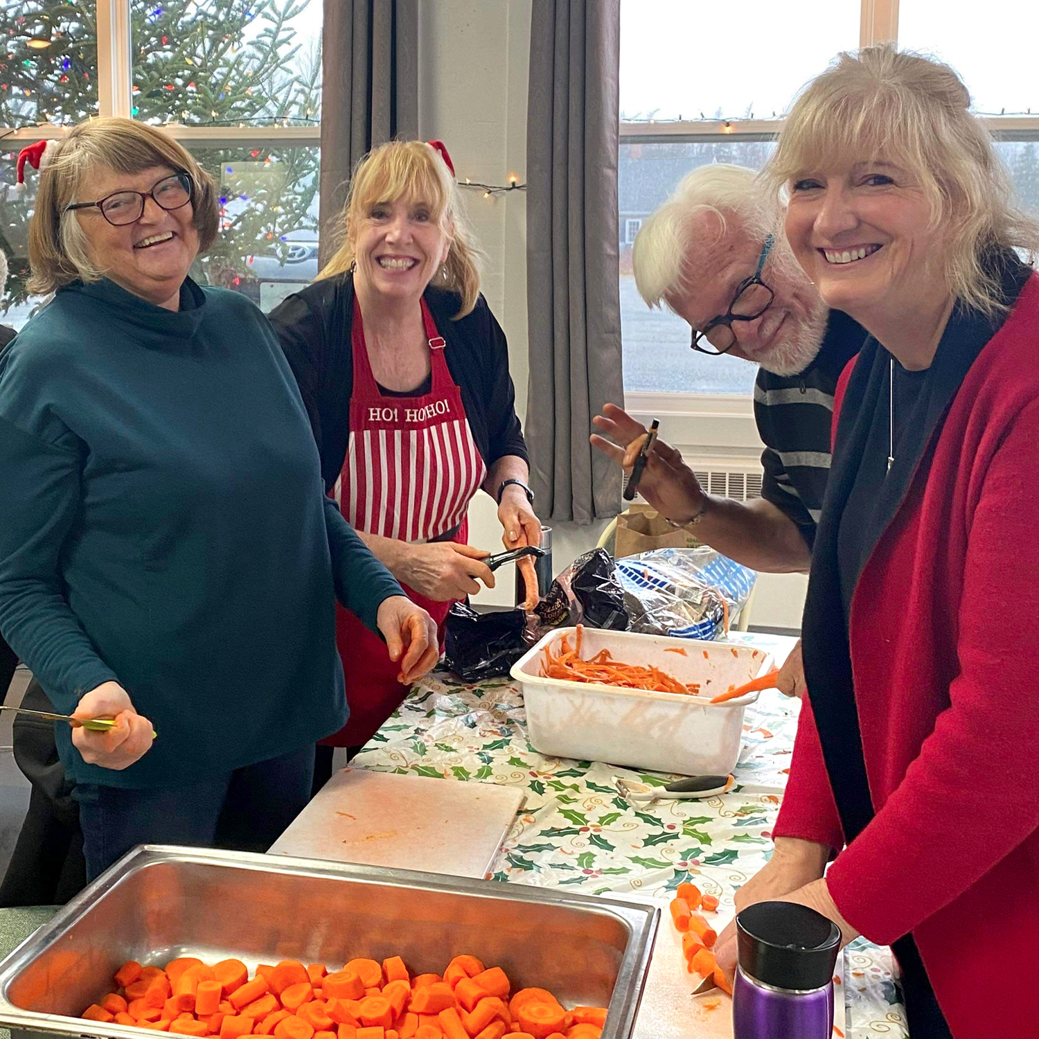 Photo four volunteers prepping carrots for a community free dinner. 